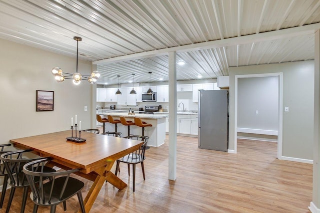 dining room featuring baseboards, light wood finished floors, and a notable chandelier