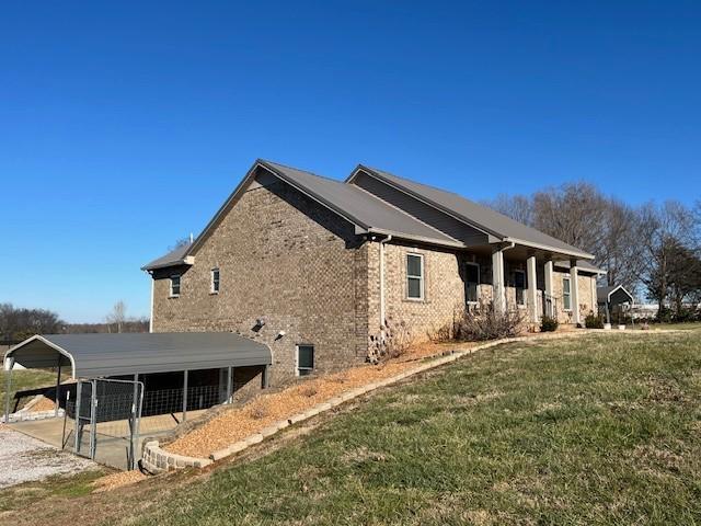 view of side of property featuring a detached carport, brick siding, and a yard