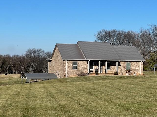 exterior space featuring brick siding, metal roof, and a front lawn