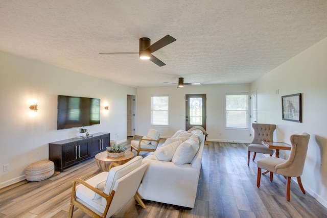 living area with a textured ceiling, wood finished floors, a ceiling fan, and baseboards