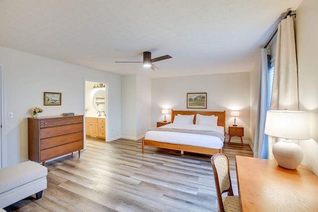 bedroom featuring baseboards, a textured ceiling, light wood finished floors, and ensuite bathroom