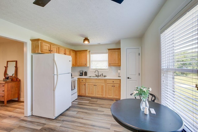 kitchen with white appliances, light wood-style flooring, light countertops, and a sink