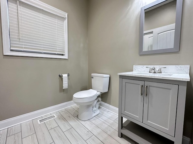 bathroom featuring wood finish floors, visible vents, toilet, vanity, and baseboards