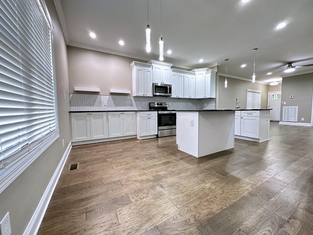 kitchen featuring decorative light fixtures, dark countertops, decorative backsplash, appliances with stainless steel finishes, and white cabinetry