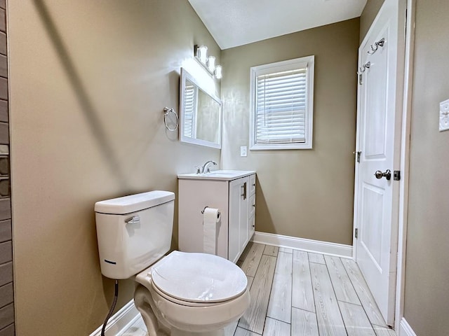 bathroom featuring vanity, wood finished floors, toilet, and baseboards