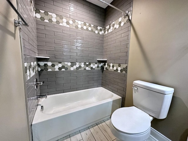 bathroom with toilet, shower / tub combination, and baseboards