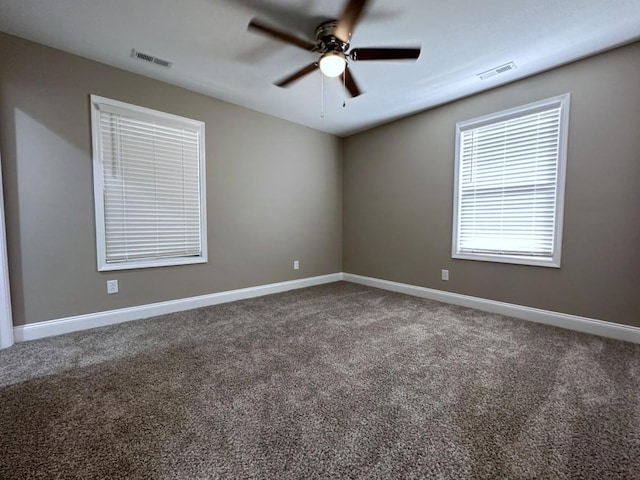 carpeted spare room with baseboards, visible vents, and ceiling fan