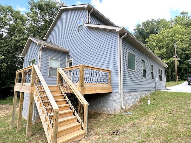 exterior space with stairs, a deck, and a lawn