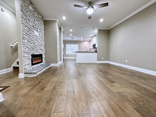 unfurnished living room with ceiling fan, stairway, wood finished floors, and crown molding