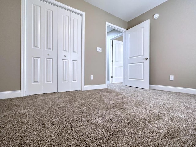 unfurnished bedroom featuring carpet floors, baseboards, and a closet