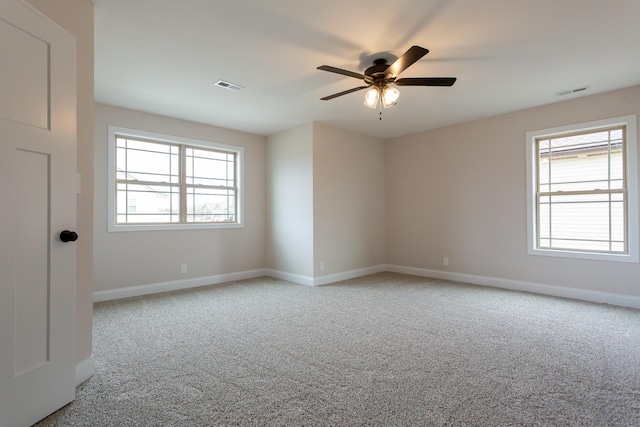 carpeted empty room with visible vents, ceiling fan, and baseboards