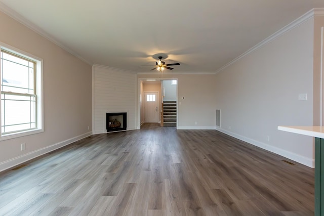 unfurnished living room with wood finished floors, a fireplace, crown molding, and stairs