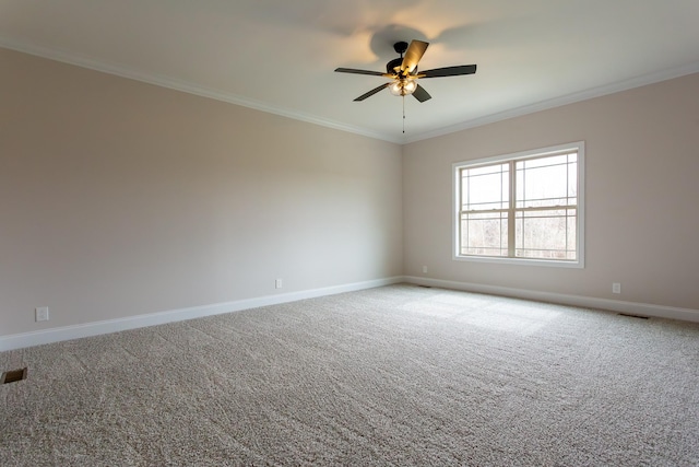 spare room featuring carpet flooring, visible vents, crown molding, and baseboards