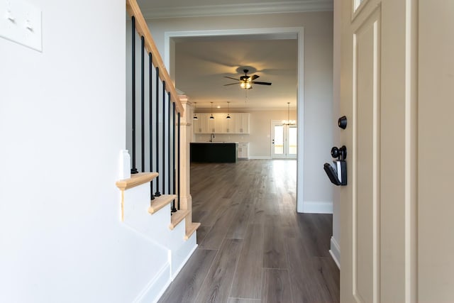 hallway with dark wood-style flooring, a sink, baseboards, stairs, and ornamental molding