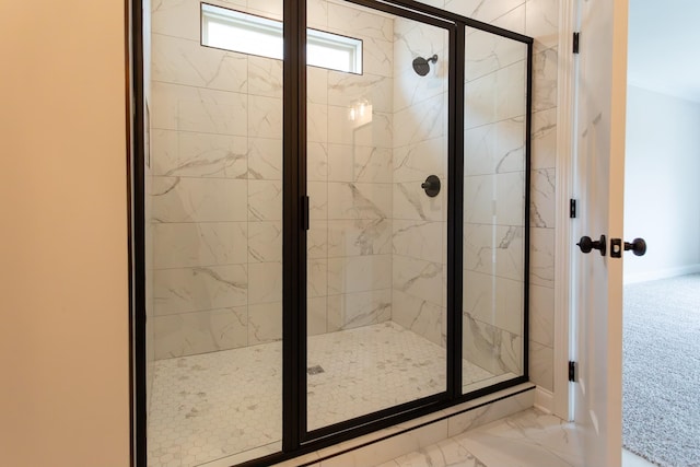 bathroom featuring marble finish floor, a shower stall, and baseboards