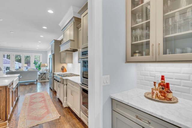 kitchen with recessed lighting, stainless steel appliances, dark wood-type flooring, ornamental molding, and glass insert cabinets