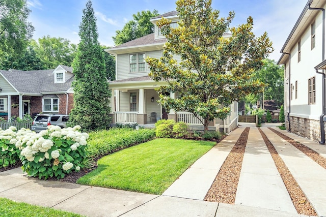 american foursquare style home with covered porch and a front yard