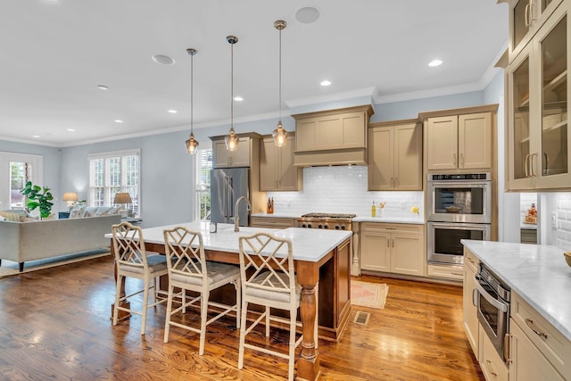 kitchen with a breakfast bar area, open floor plan, appliances with stainless steel finishes, backsplash, and dark wood finished floors