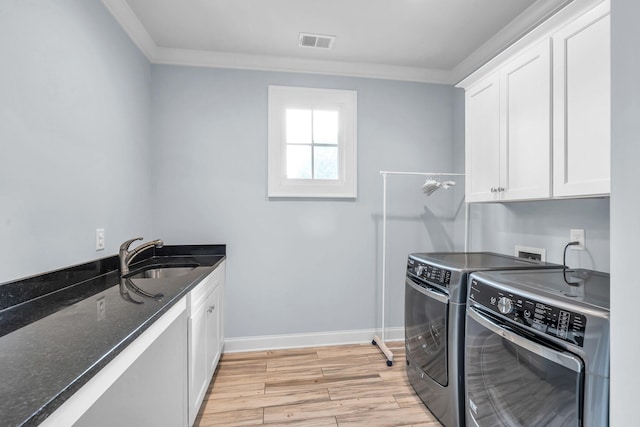 kitchen with visible vents, washer and dryer, light wood-style floors, white cabinetry, and a sink