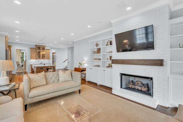 living room featuring a fireplace, crown molding, and wood finished floors