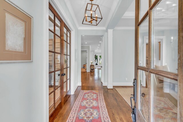 entryway with french doors, a notable chandelier, crown molding, dark wood-type flooring, and baseboards