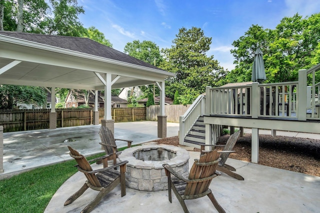 view of patio / terrace with an outdoor fire pit, fence, and a carport