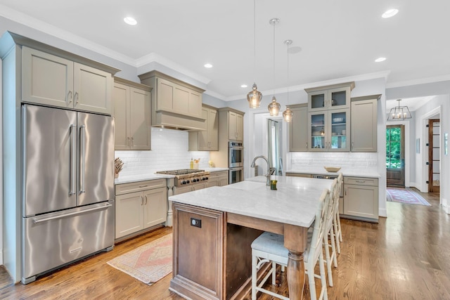 kitchen with stainless steel appliances, gray cabinets, a center island with sink, and dark wood-style flooring