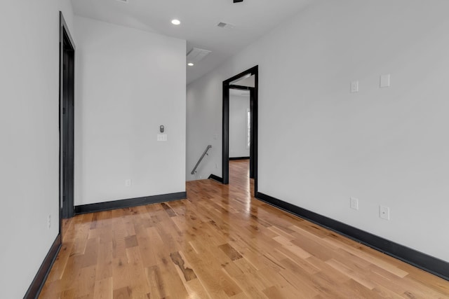 unfurnished room with attic access, visible vents, baseboards, light wood-type flooring, and recessed lighting