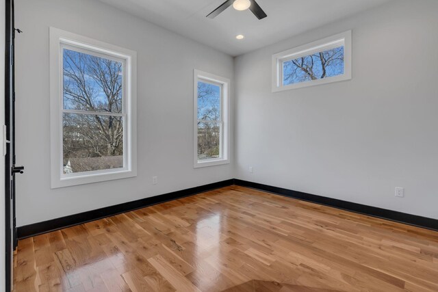 empty room with a ceiling fan, a healthy amount of sunlight, baseboards, and wood finished floors