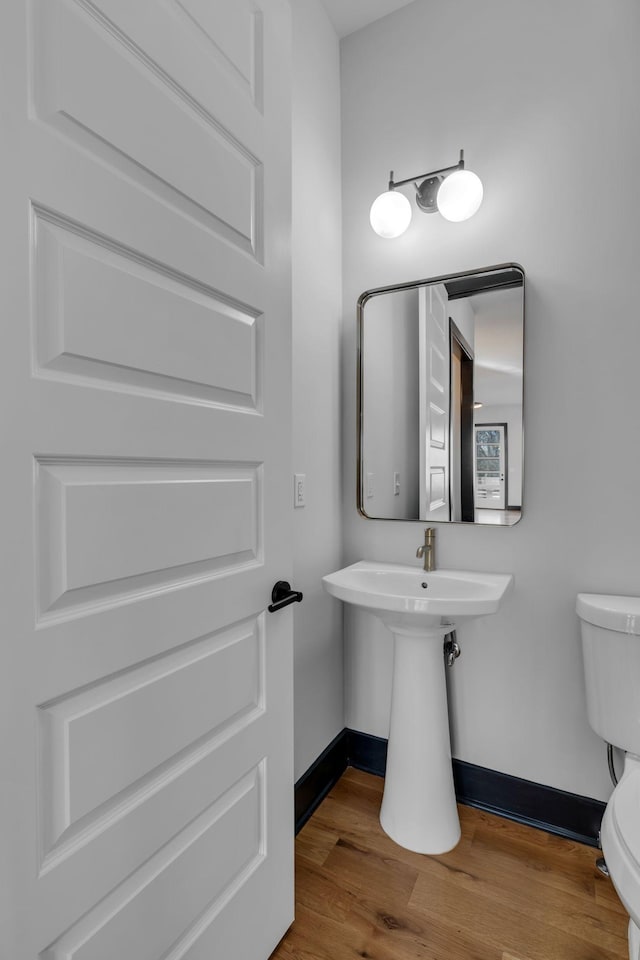 bathroom featuring toilet, baseboards, and wood finished floors