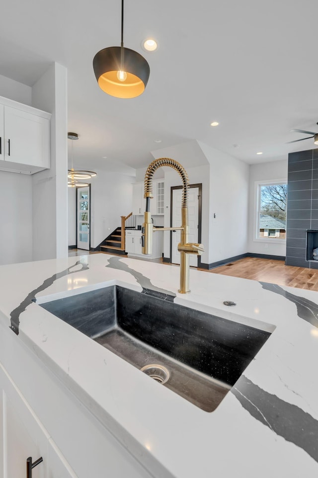 interior space with pendant lighting, recessed lighting, white cabinetry, a sink, and light stone countertops