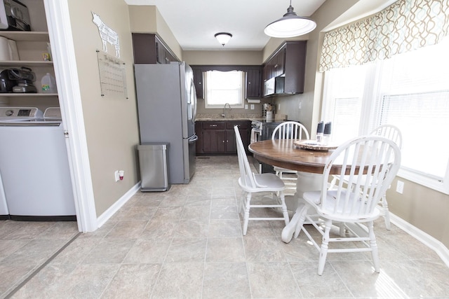 kitchen featuring washer / dryer, freestanding refrigerator, baseboards, and dark brown cabinets