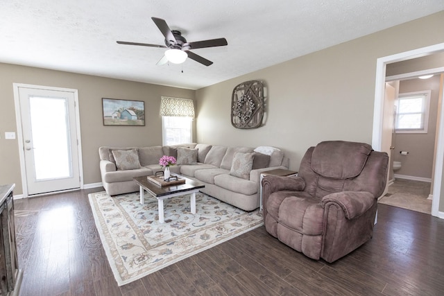 living room featuring dark wood-type flooring, a wealth of natural light, baseboards, and a ceiling fan