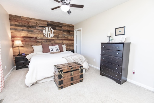 carpeted bedroom with an accent wall, wood walls, a ceiling fan, and baseboards