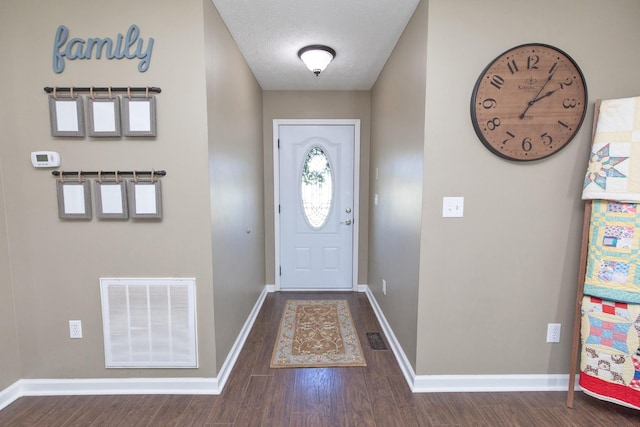 entrance foyer featuring visible vents, a textured ceiling, baseboards, and wood finished floors