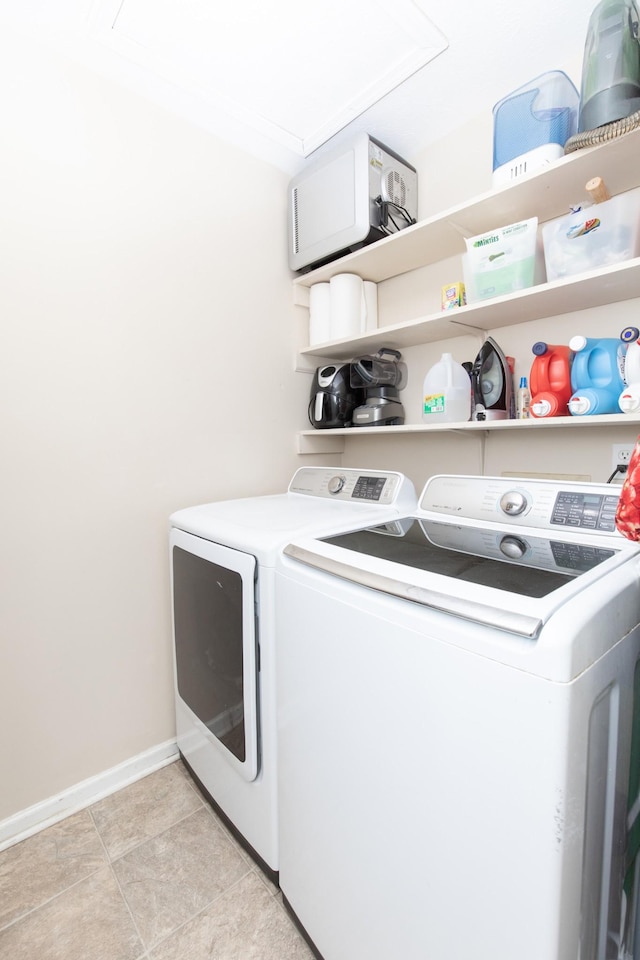 laundry area featuring light tile patterned floors, laundry area, washing machine and clothes dryer, and baseboards