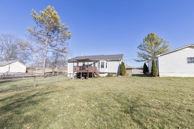 rear view of house with a deck, a yard, and fence