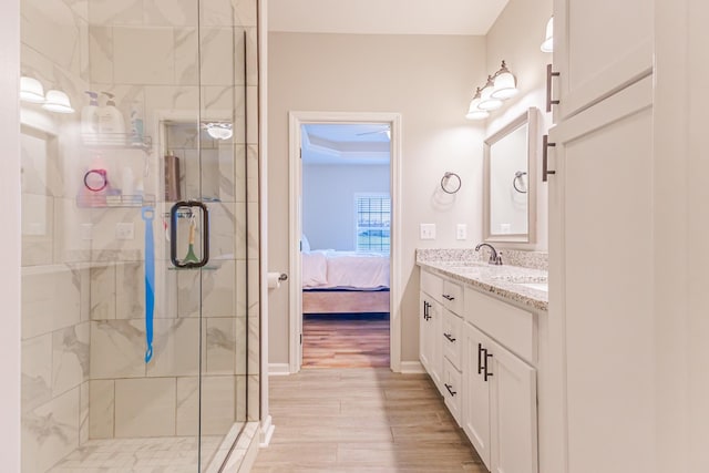 ensuite bathroom featuring double vanity, a stall shower, wood finished floors, ensuite bathroom, and a sink