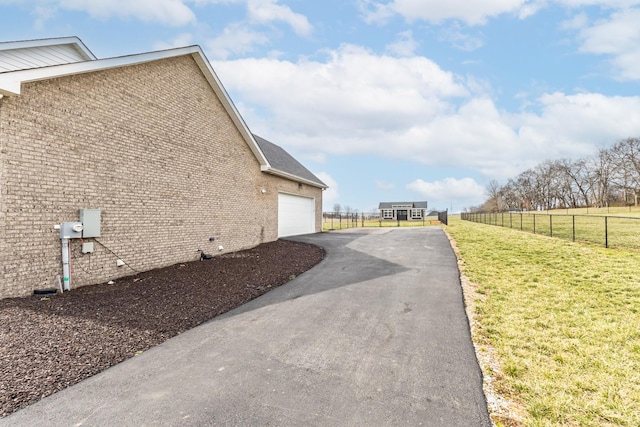 view of property exterior featuring a yard, fence, and brick siding