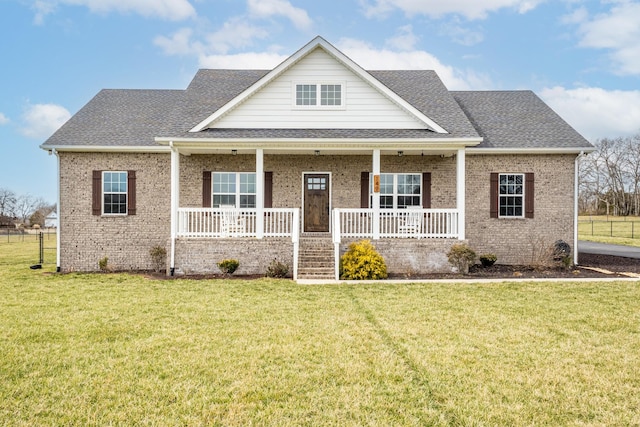 view of front of house with a porch, a shingled roof, brick siding, and a front yard