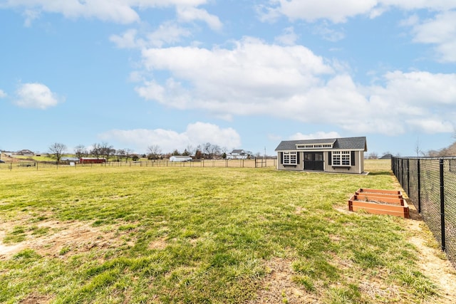 view of yard featuring a fenced backyard, a rural view, and an outbuilding