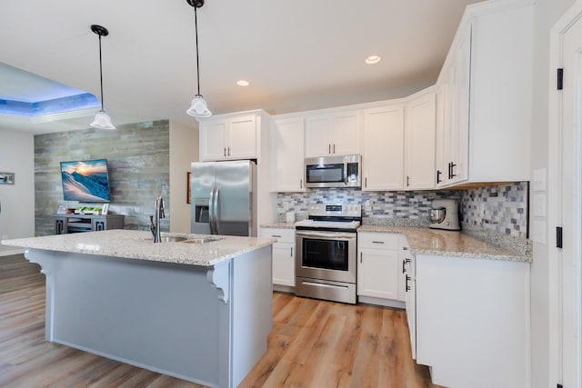 kitchen featuring appliances with stainless steel finishes, a sink, light wood-style flooring, and tasteful backsplash