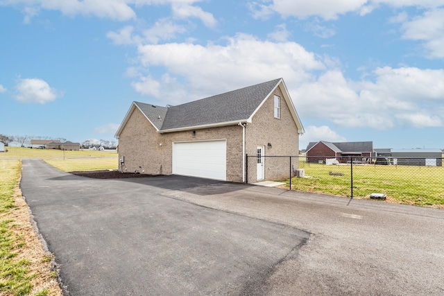 view of property exterior featuring aphalt driveway, brick siding, a lawn, and fence