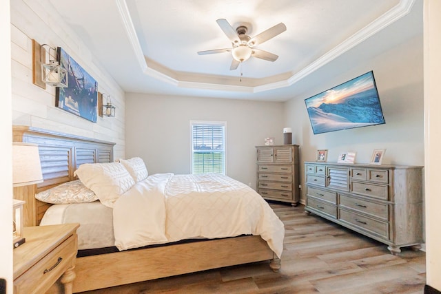 bedroom featuring ceiling fan, wood finished floors, a raised ceiling, and crown molding