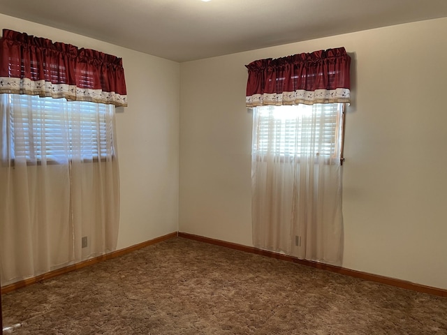 spare room featuring plenty of natural light, carpet flooring, and baseboards