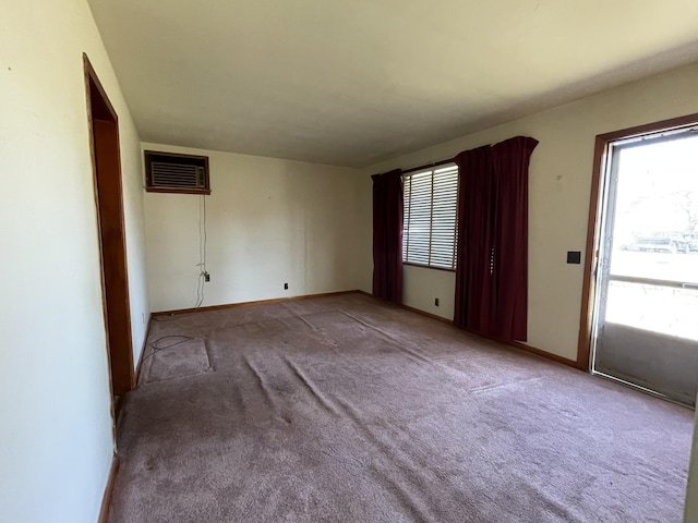 spare room featuring carpet, baseboards, and a wall mounted AC