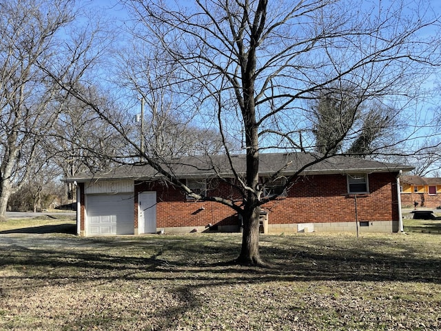 view of front of property featuring dirt driveway, brick siding, a front lawn, and an attached garage