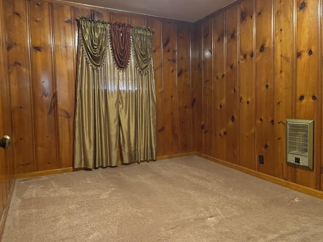 carpeted empty room featuring baseboards, wood walls, and heating unit