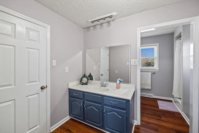 bathroom with visible vents, vanity, a textured ceiling, and wood finished floors