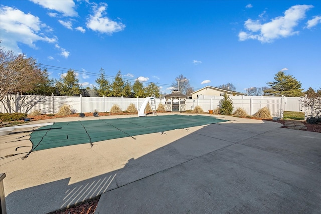 view of swimming pool featuring a patio area, a fenced backyard, a fenced in pool, and a water slide